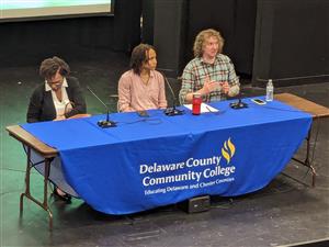 three panelists sit at a table with a blue DCCC table cloth